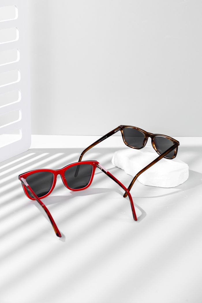 A pair of modern sunglasses showcased on a white minimalist setting with shadows.